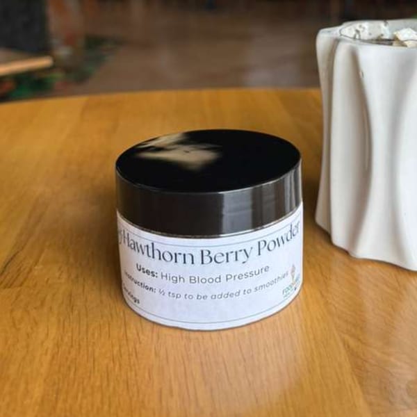 A jar of Hawthorn Berry Powder for high blood pressure on a wooden table.