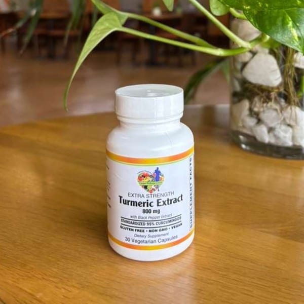 White bottle of Extra Strength Turmeric Extract 800mg with black pepper extract on a wooden table.