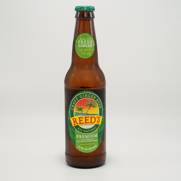 A bottle of Reed's Craft Ginger Beer, with a green label featuring palm trees and a beach scene.