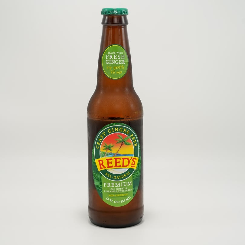 A bottle of Reed's Craft Ginger Beer, with a green label featuring palm trees and a beach scene.