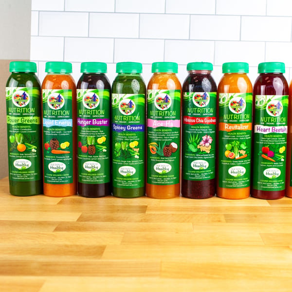 Eight colorful bottled juices from FoodAMed, each with a green label detailing ingredients and health benefits.