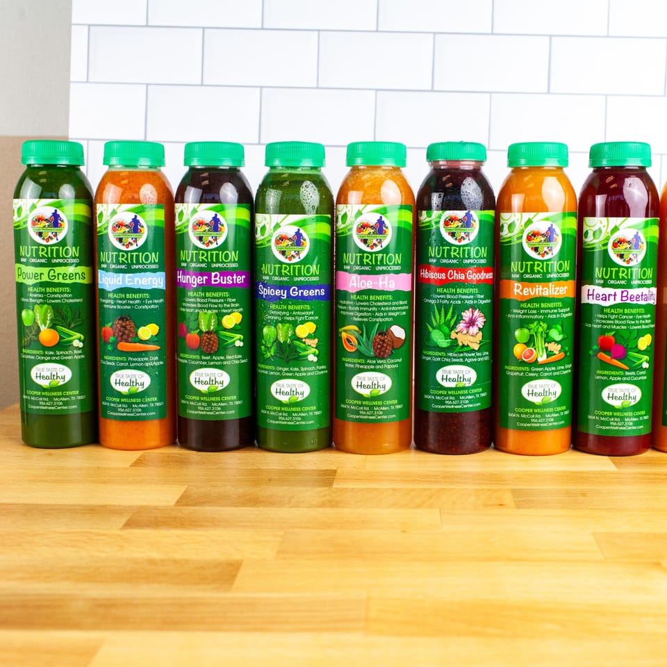 Eight colorful bottled juices from FoodAMed, each with a green label detailing ingredients and health benefits.