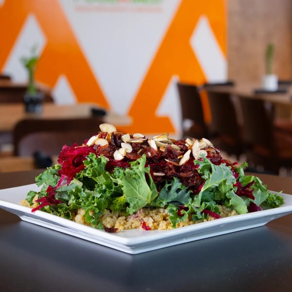 FoodAMed's healthy quinoa and kale salad topped with beets, dried fruit, and sliced almonds.
