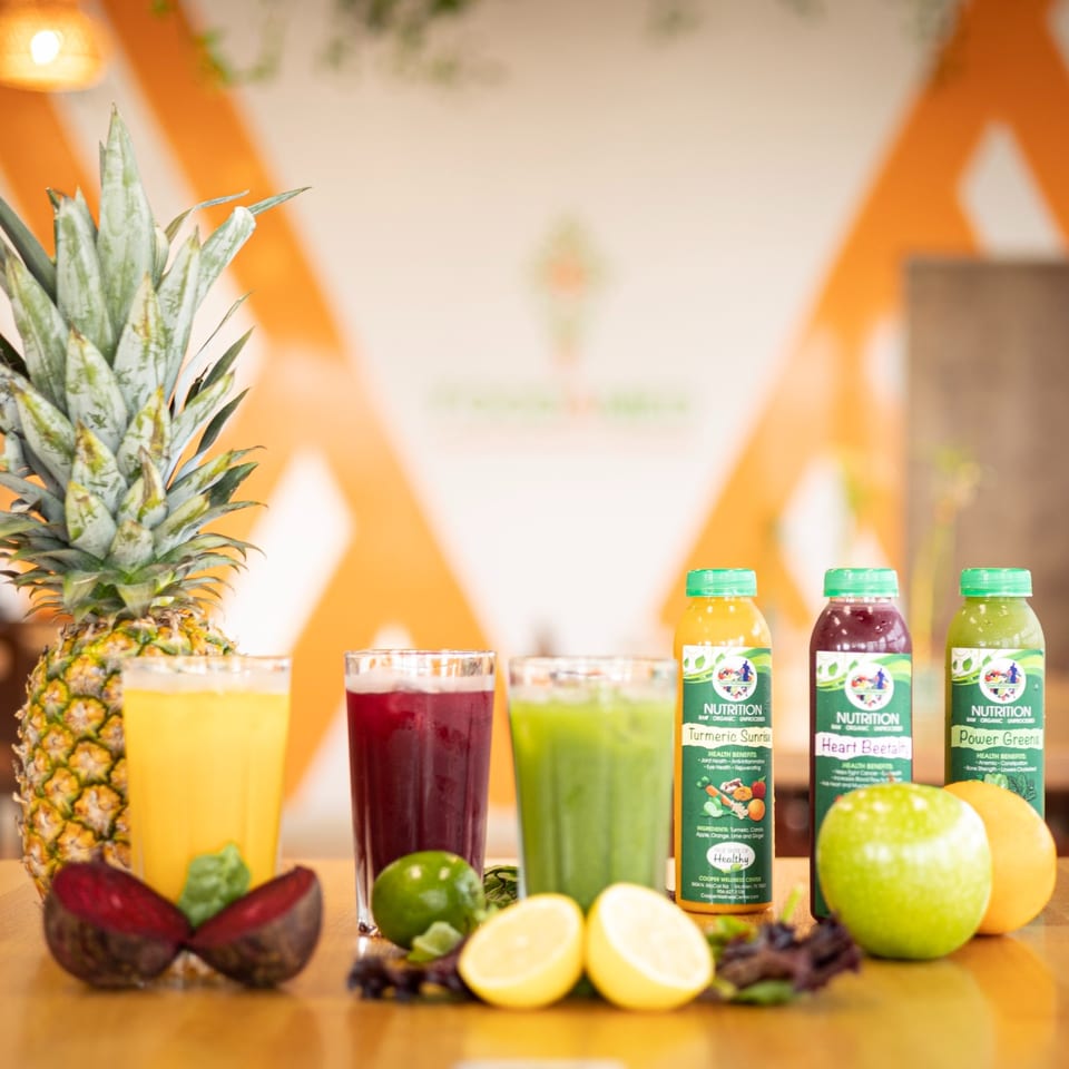 Fresh juices and whole fruits, including pineapple, beets, limes, lemons, green apple, and orange.