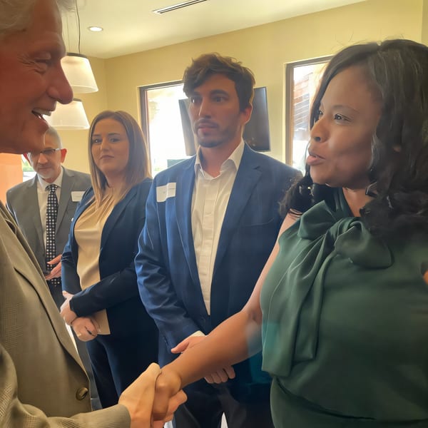 People in business attire shaking hands and conversing at a FoodAMed event.
