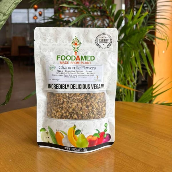 A Foodamed Chamomile Flowers tea pouch, labeled "Incredibly Delicious Vegan," sits on a wooden table.