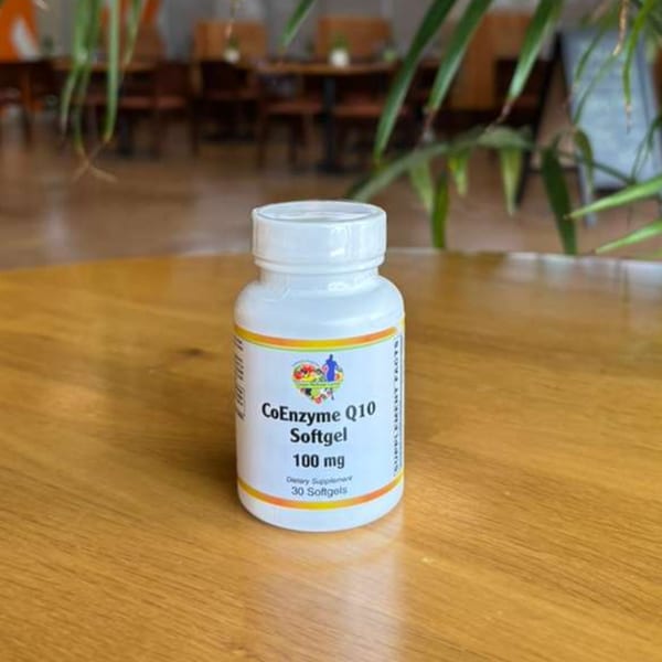 A white bottle of CoEnzyme Q10 Softgel 100 mg dietary supplement on a wooden table.