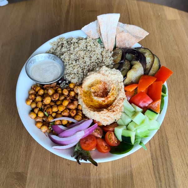 FoodAMed's healthy bowl with quinoa, hummus, roasted chickpeas, vegetables, and pita bread.