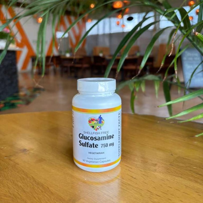 A white bottle of Glucosamine Sulfate 750 mg dietary supplement on a wooden table.