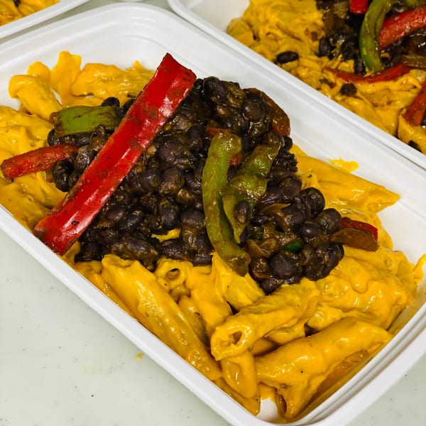 Healthy FoodAMed meal with pasta, black beans, red and green bell peppers in a white container.