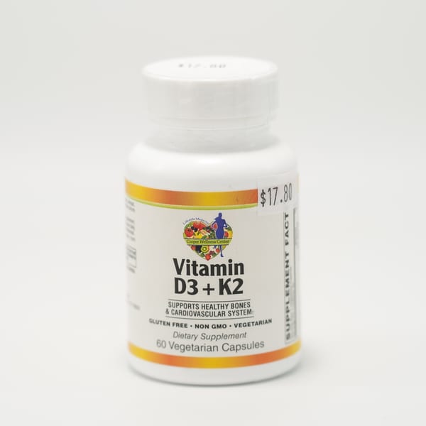 A white bottle of Cooper Wellness Center Vitamin D3 + K2 dietary supplement with a $17.80 price tag.