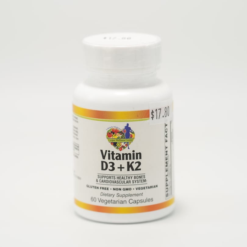 A white bottle of Cooper Wellness Center Vitamin D3 + K2 dietary supplement with a $17.80 price tag.