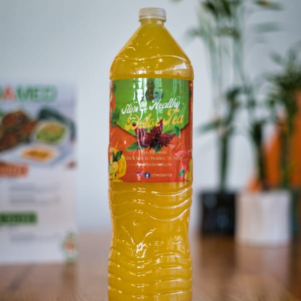 A large bottle of yellow "Slim & Healthy Detox Tea" from FoodAMed on a wooden table.