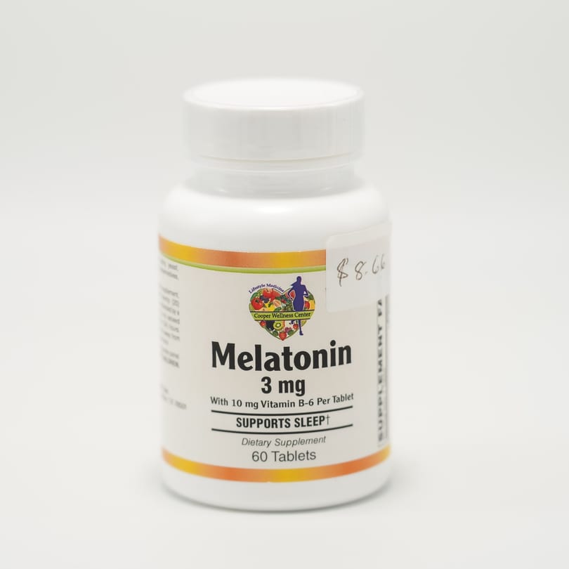 A white bottle of Melatonin 3 mg dietary supplement with a Cooper Wellness Center label.