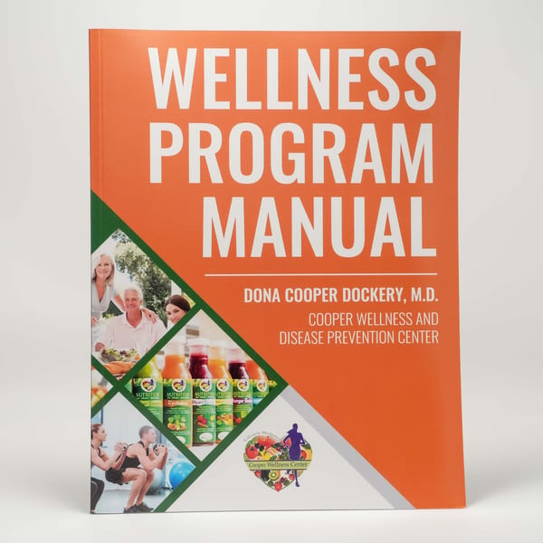 Orange "Wellness Program Manual" book with images of healthy people, juices, and the Cooper Wellness Center logo.