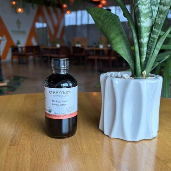 A bottle of Starwest Botanicals Ginkgo Leaf Herbal Extract next to a potted snake plant.